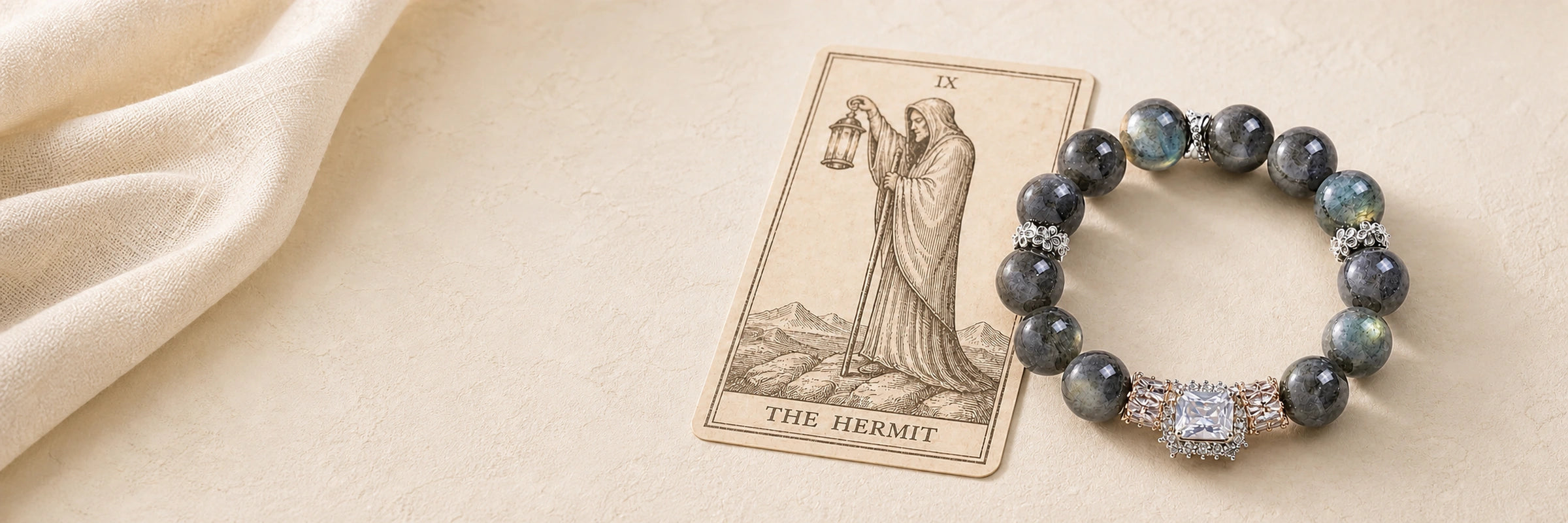 Hermit-inspired VouSseka crystal bracelet arranged with a tarot card on warm ivory linen.